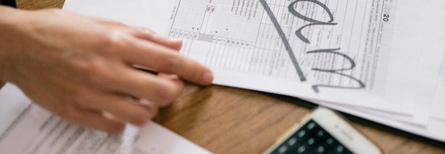 Close-up of hands examining documents marked 'scam' with a calculator nearby.