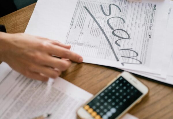 Close-up of hands examining documents marked 'scam' with a calculator nearby.